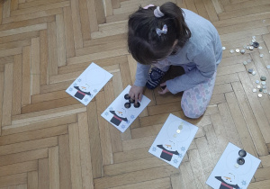 Dziewczynka układa sylwetę bałwanka z gotowych elementów.